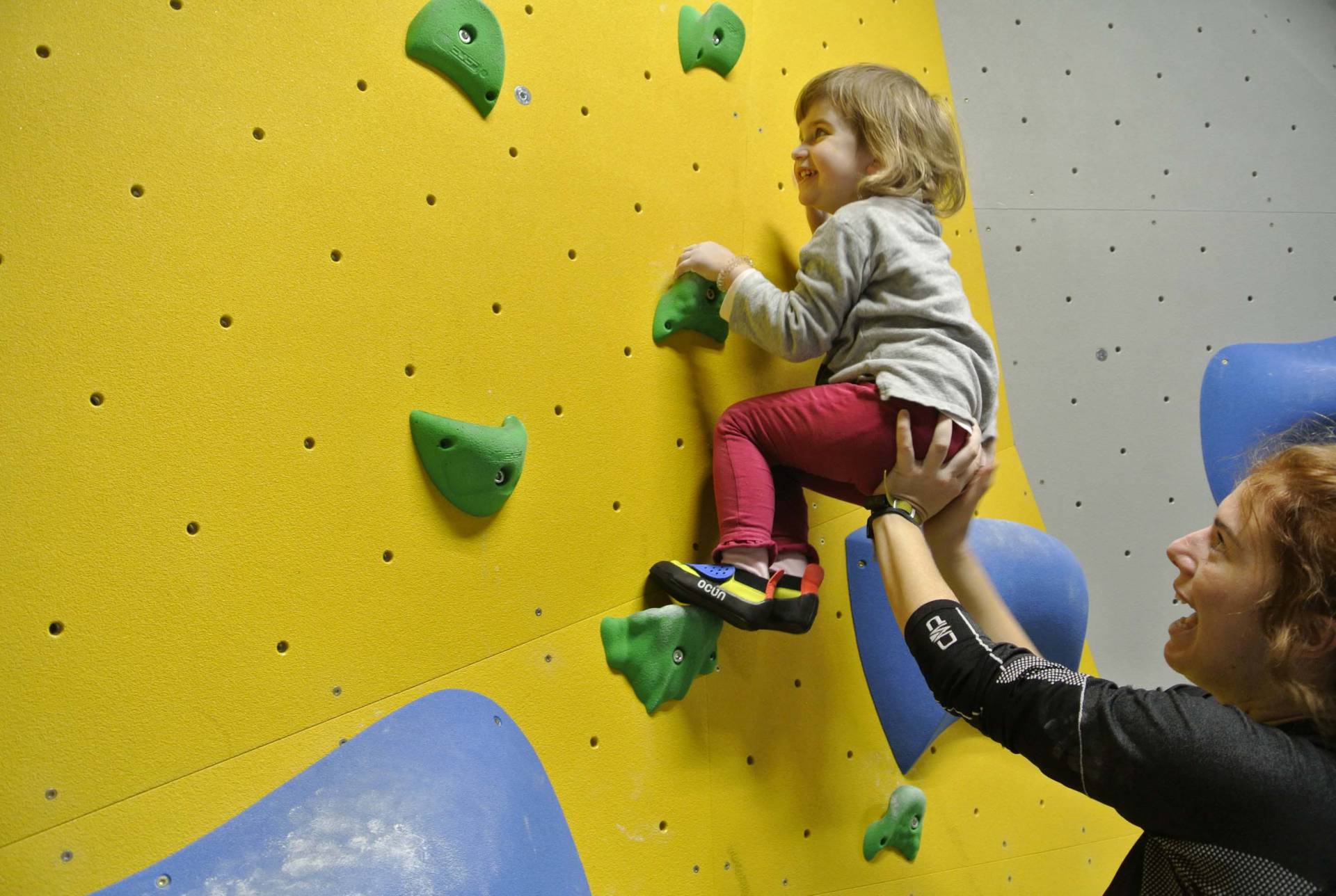 Mama hilft der kleinen Tochter an der Boulderwand