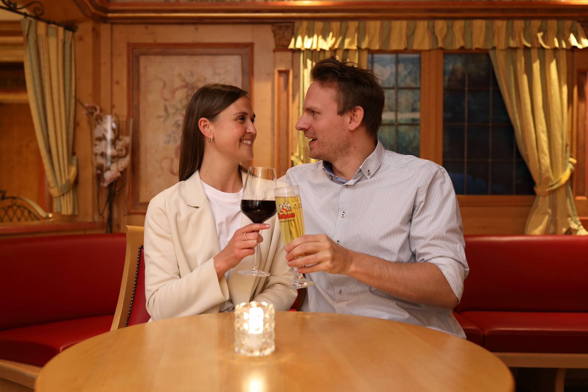 Paar am Tisch stoßen mit Wein und Bier an