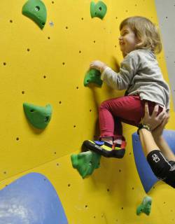Mama hilft der kleinen Tochter an der Boulderwand