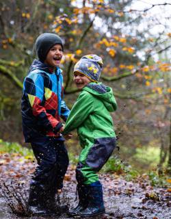 Zwei Jungs springen in Schlammpfütze im Wald