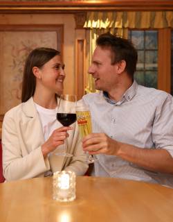 Paar am Tisch stoßen mit Wein und Bier an