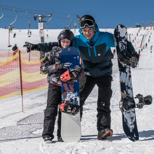 Papa und Sohn mit Snowboard auf der Piste am Feldberg