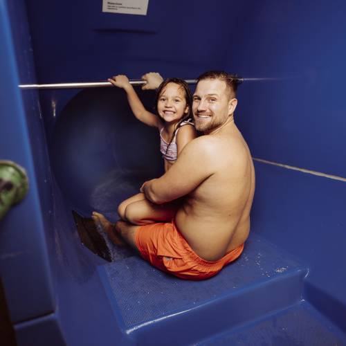 Papa und Tochter sitzen am Eingang der Röhrenrutsche