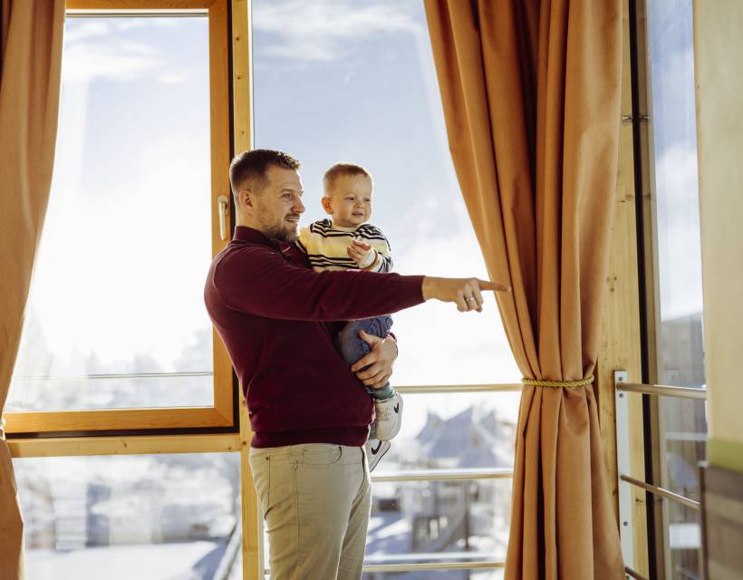 Papa mit Sohn auf dem Arm schauen aus dem Fenster