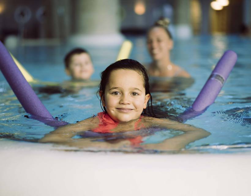 Familie im Pool mit Schwimmnudeln