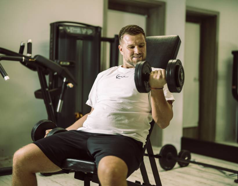 Mann im Fitnessstudio trainiert mit Kurzhanteln