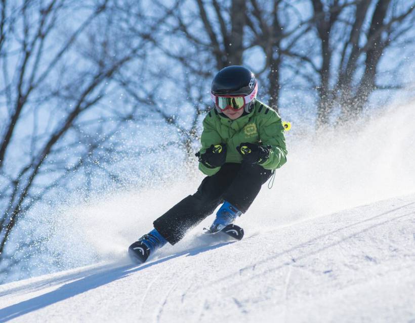 Kind saust auf Ski die Piste runter