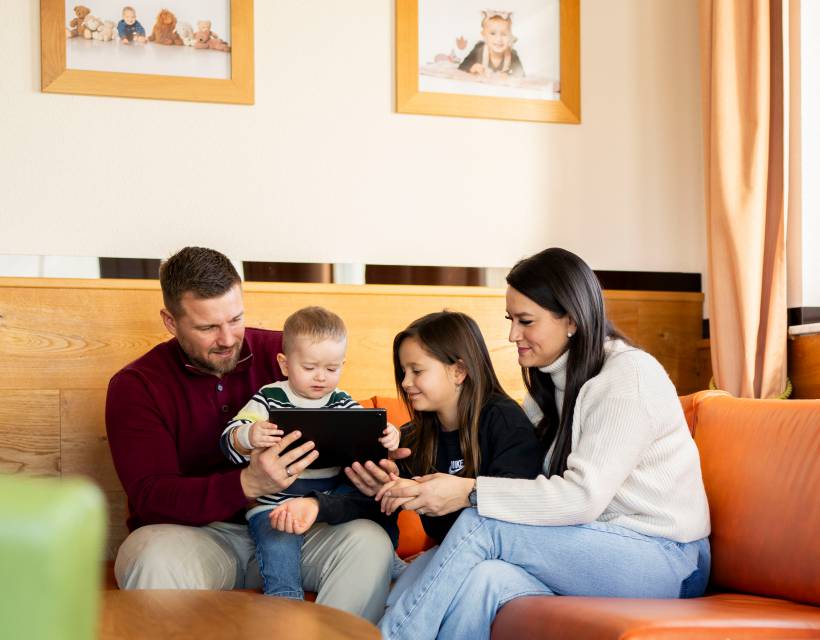 Familie im Hotelzimmer am Tablet