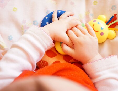 Babyhände halten Spielzeug