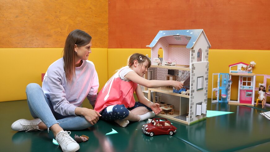 Mutter und Tochter spielen mit Puppenhaus