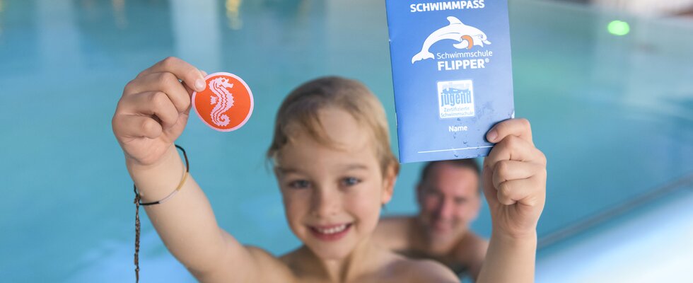 Junge hält Flipper Schwimmpass in die Kamera