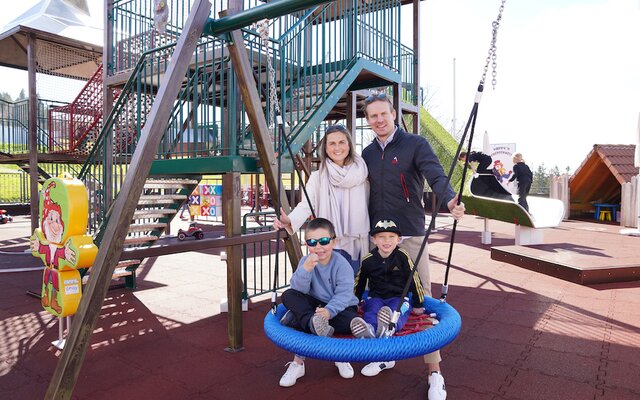 Familie auf der Netzschaukel am Kleinkinder-Spielplatz