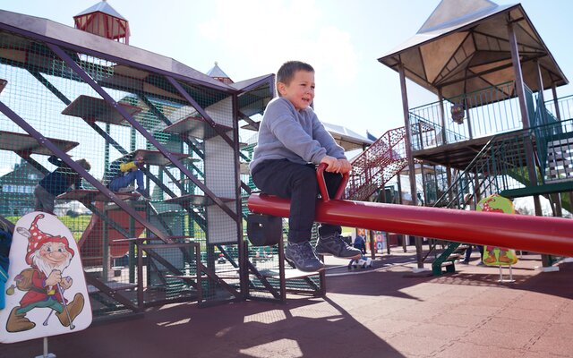 Junge auf Wippe am Kleinkinder-Spielplatz