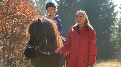 Mutter führt Tochter auf Pferd im Freien